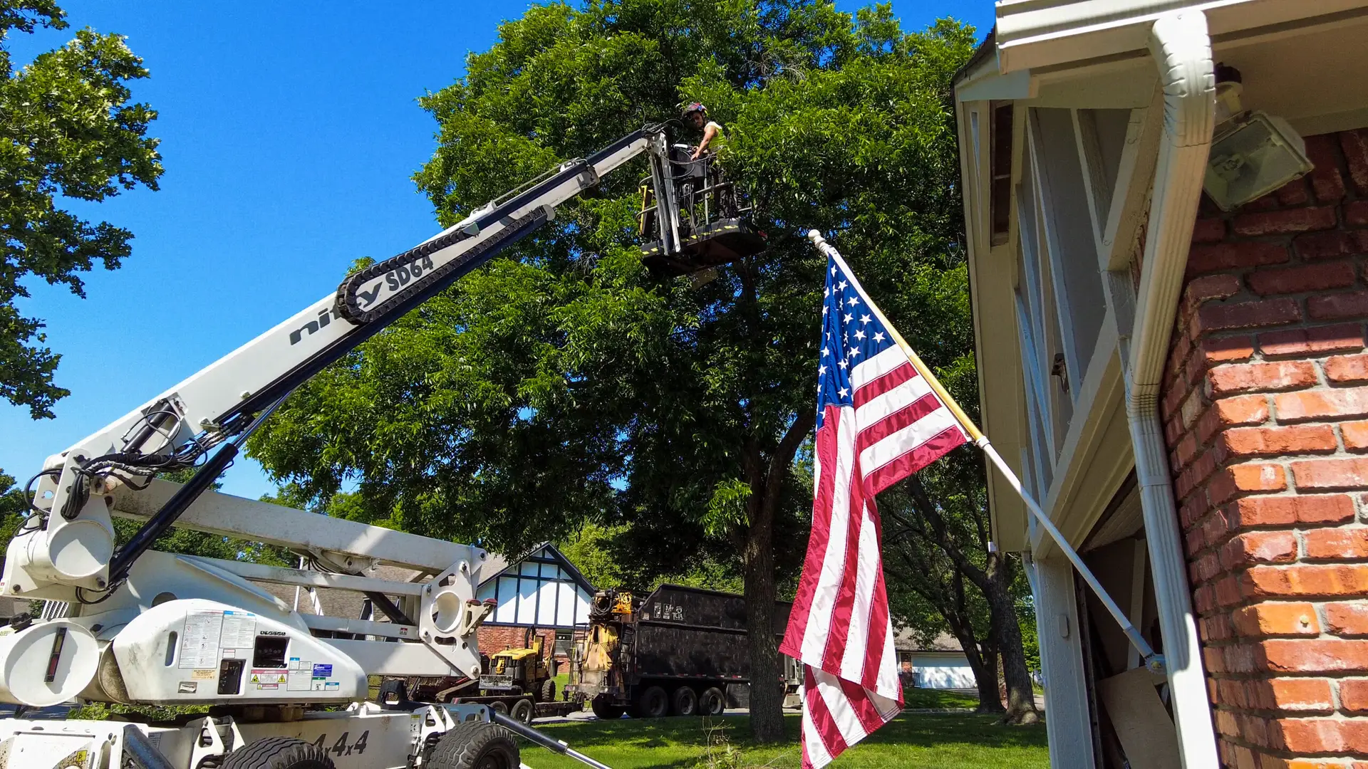 An image of a team membmer using a lift to access the top of a tree to perform Tree Care